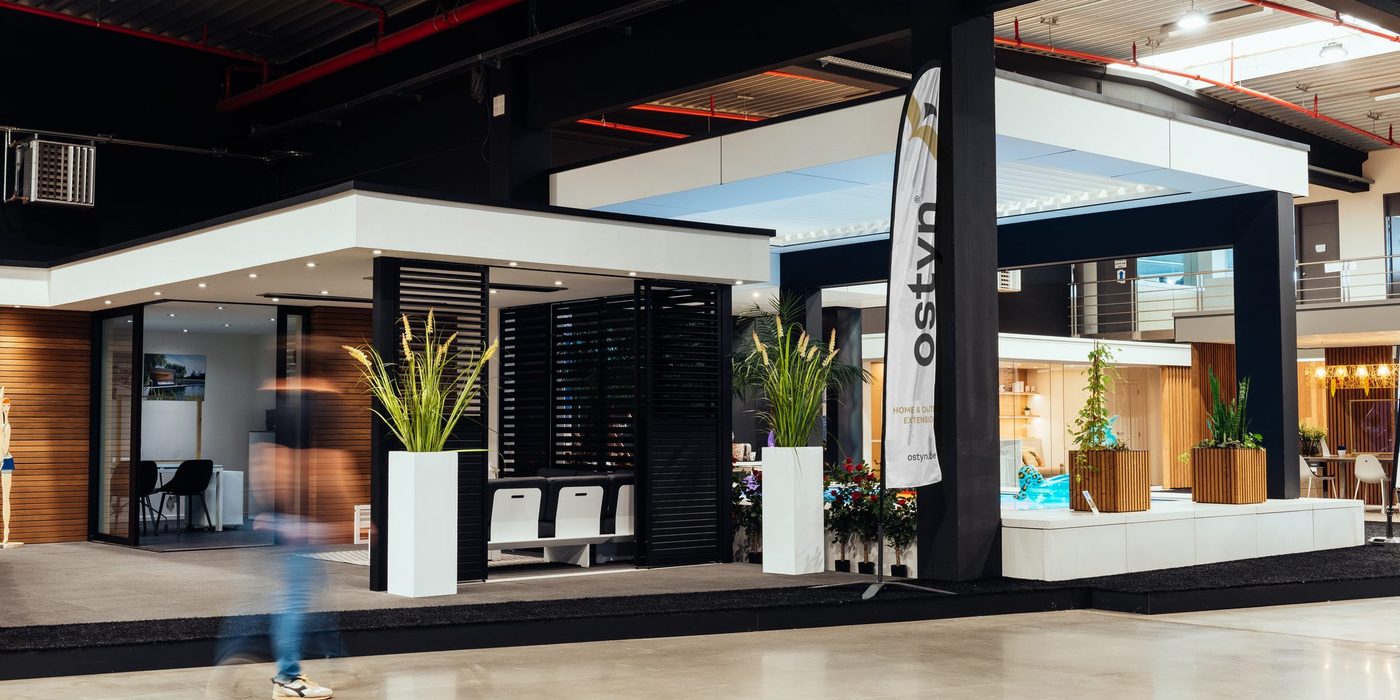 Overdekte showroom van Ostyn in Dottenijs met opgestelde modellen van een terrasoverkapping en een tuinkamer
